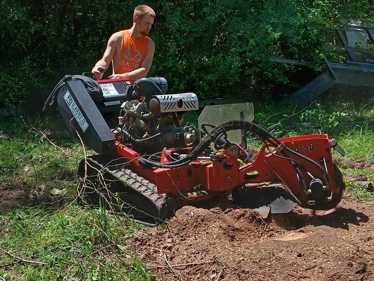 Tracked stump grinder cutting a stump down below grade